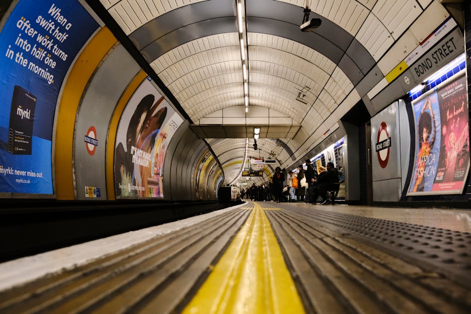 Interior view of the Knightsbridge underground station platform after a cleaning session, with a long, curved tunnel featuring white-tiled walls and a dark tunnel entrance at the far end. The platform